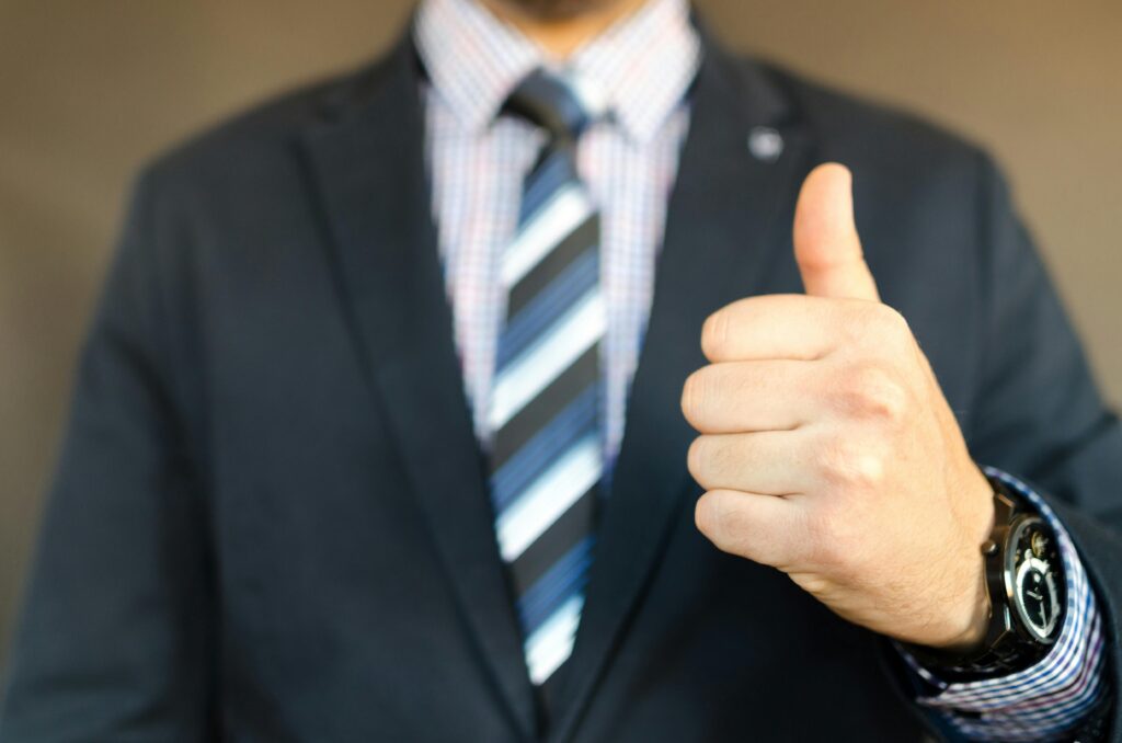 A person in a suit giving a thumbs up.